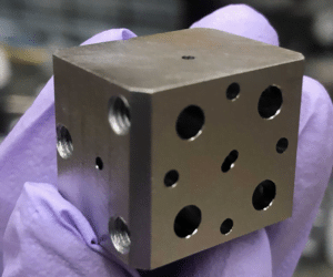 A niobium superconducting cavity. The holes lead to tunnels which intersect to trap light and atoms.